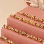 Stylish gold bracelets elegantly displayed on a pink stand with soft lighting highlights.